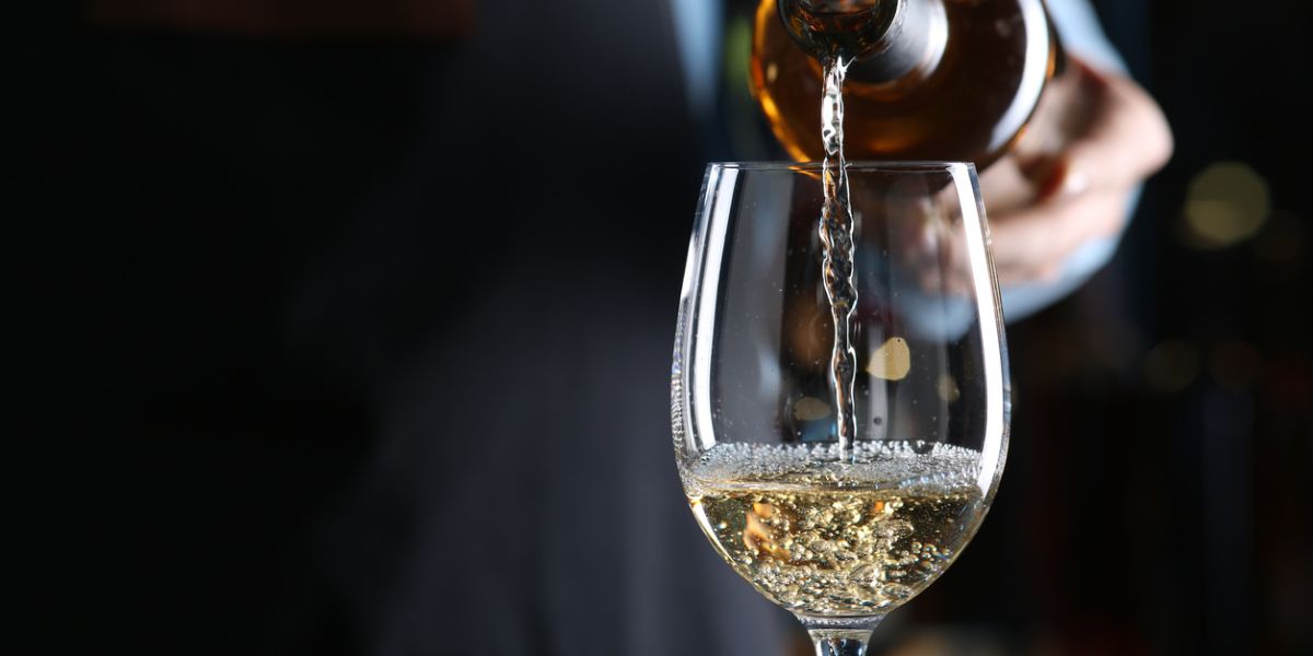 Bartender pouring white wine from bottle into glass