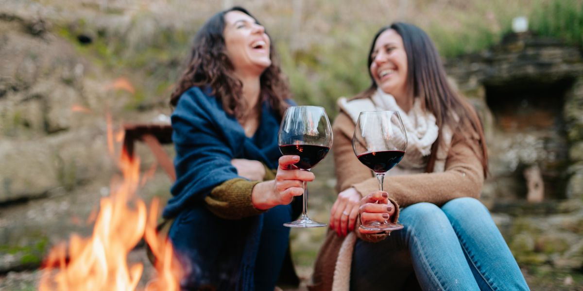 Women laughing, holding glass of red wine