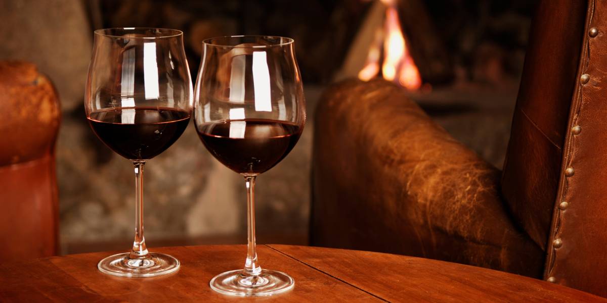 Two glasses of the best red wine in front of a fireplace.