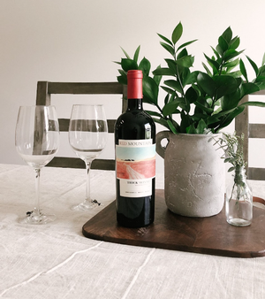 A pacific rim dry red wine on a table with two wine glasses.