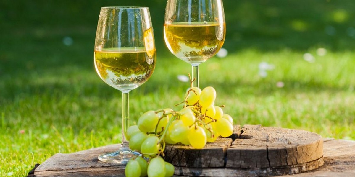 White wine with grapes on old wooden table